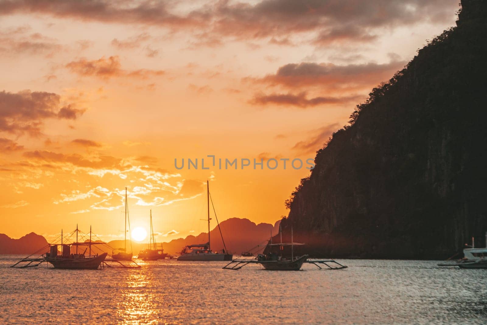 Traditional philippine boats bangka at sunset time. Beautiful sunset with silhouettes of philippine boats in El Nido, Palawan island, Philippines. Orange sky sunset paradise beach. by Busker