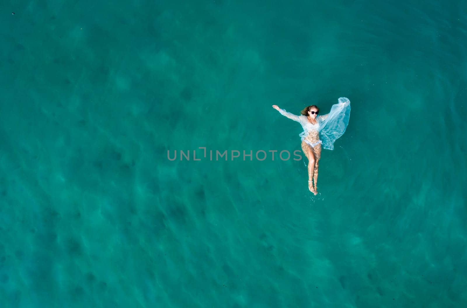 Top view of young pretty sexy girl in white swimsuit floating on water surface in crystal clear turquoise ocean.. Happy island lifestyle. Ocean relax, travel to Philippines by Busker