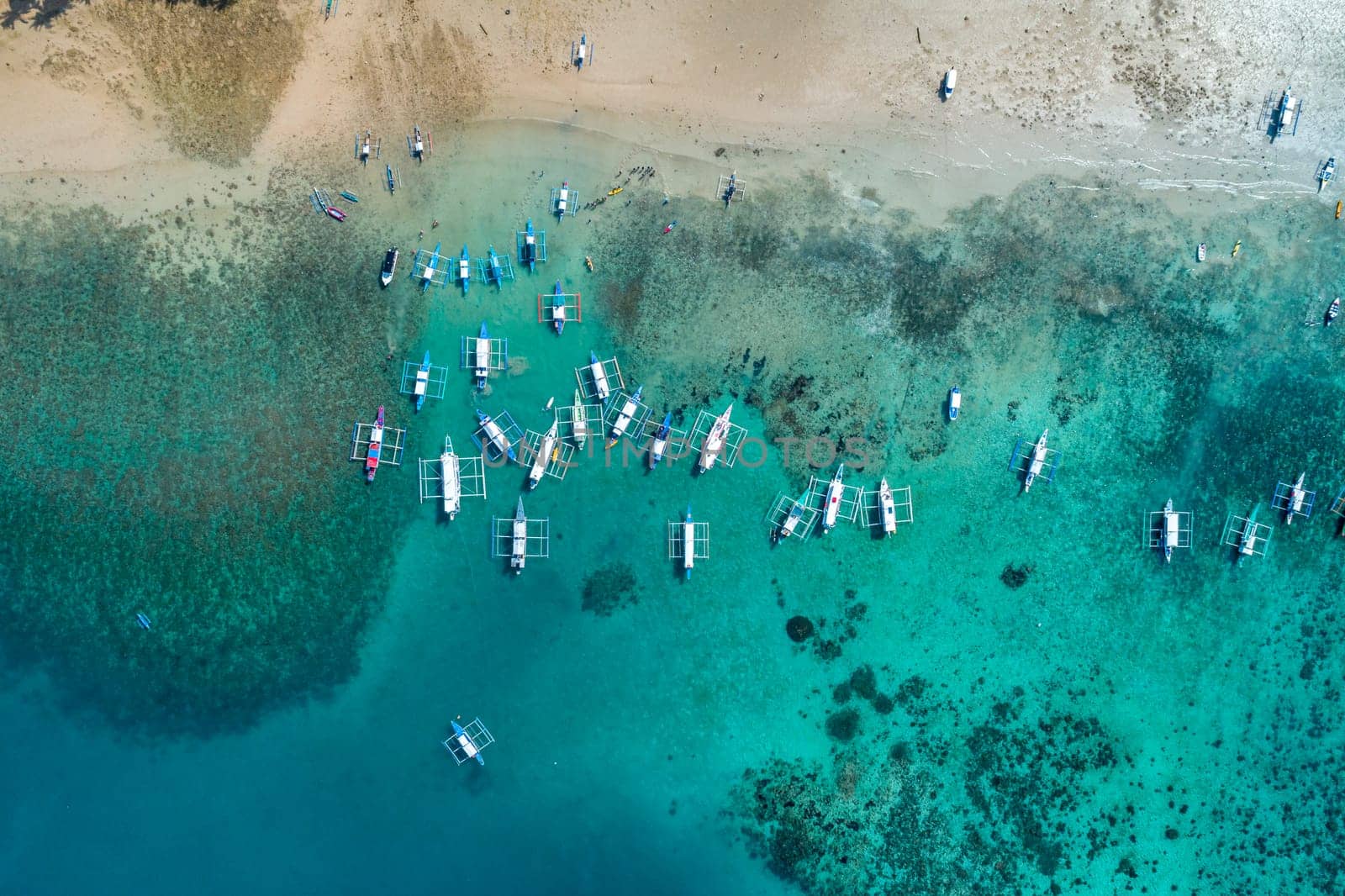 Top drone view of a traditional philippine boats on the surface of the azure water in the lagoon. Seascape with blue bay and boats view from above. Summer and travel vacation concept by Busker