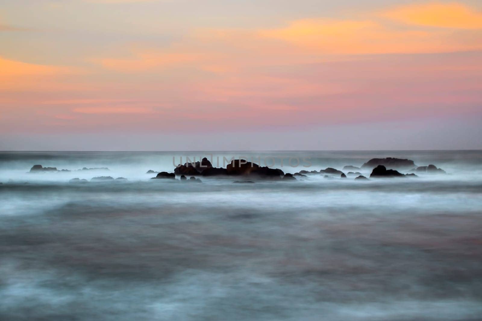 Waves crash along the coastline during sunset near San Simeon, California.