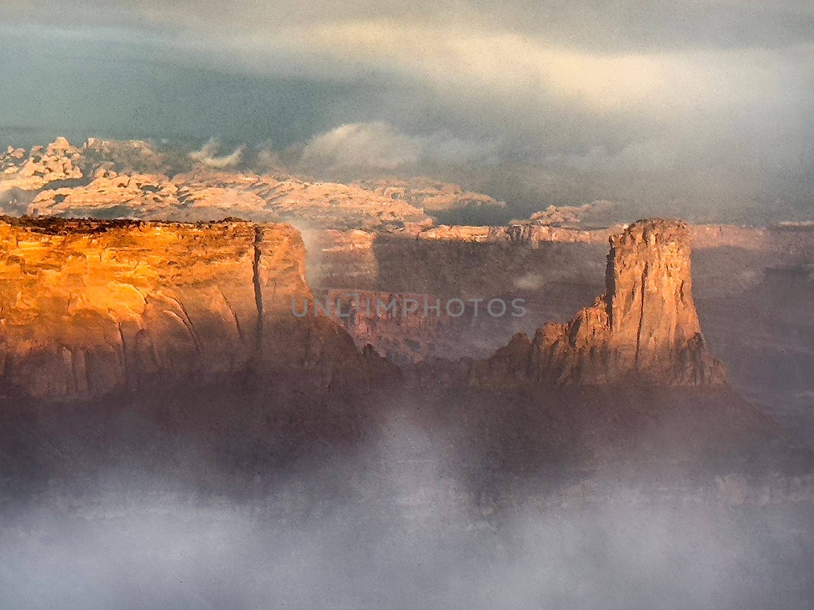 A passing rainstorm leaves residual clouds and fog as the sun penetrates the red rock landscape at Dead Horse State Park, Utah