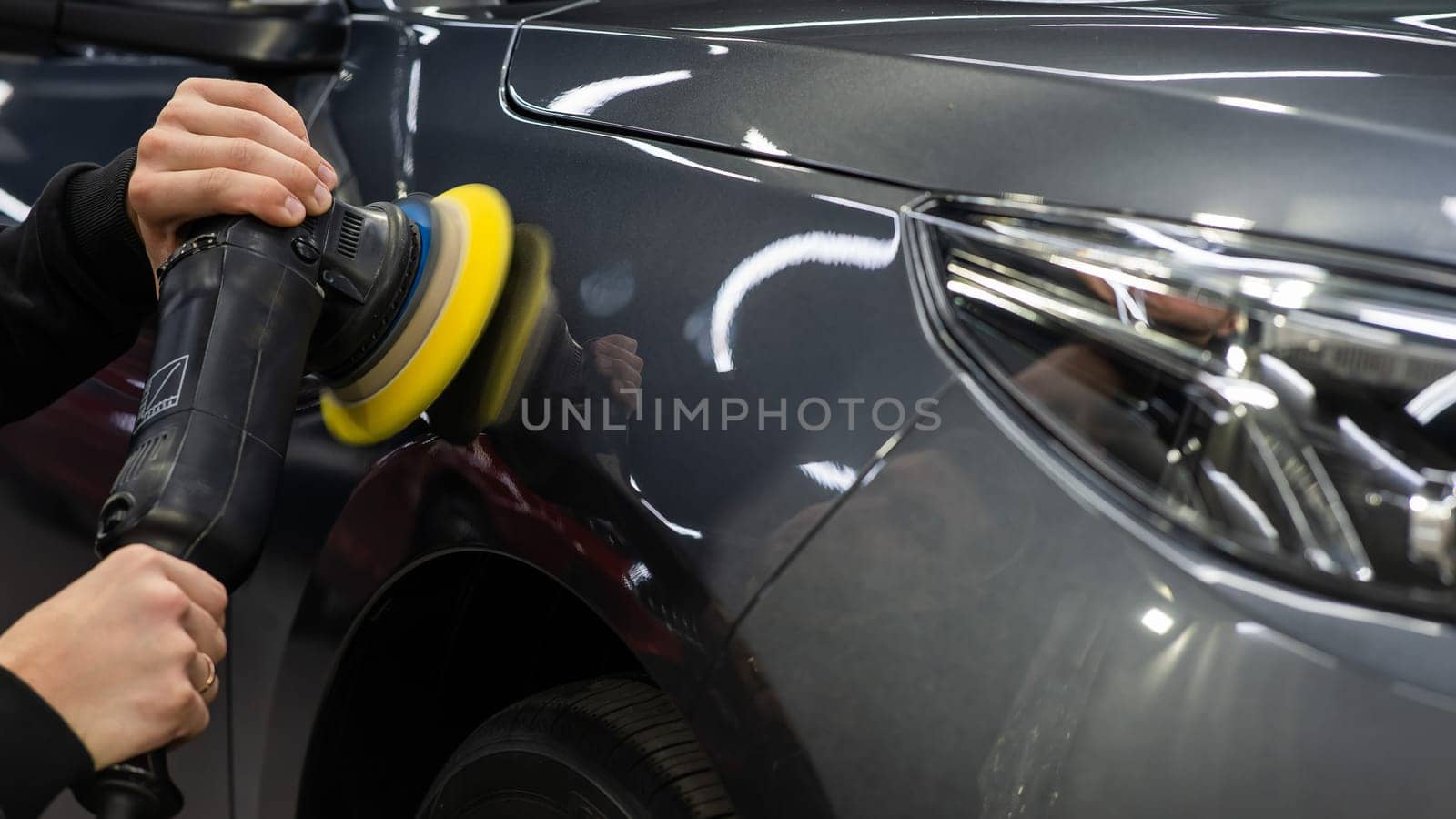A master polishes the surface of a car body
