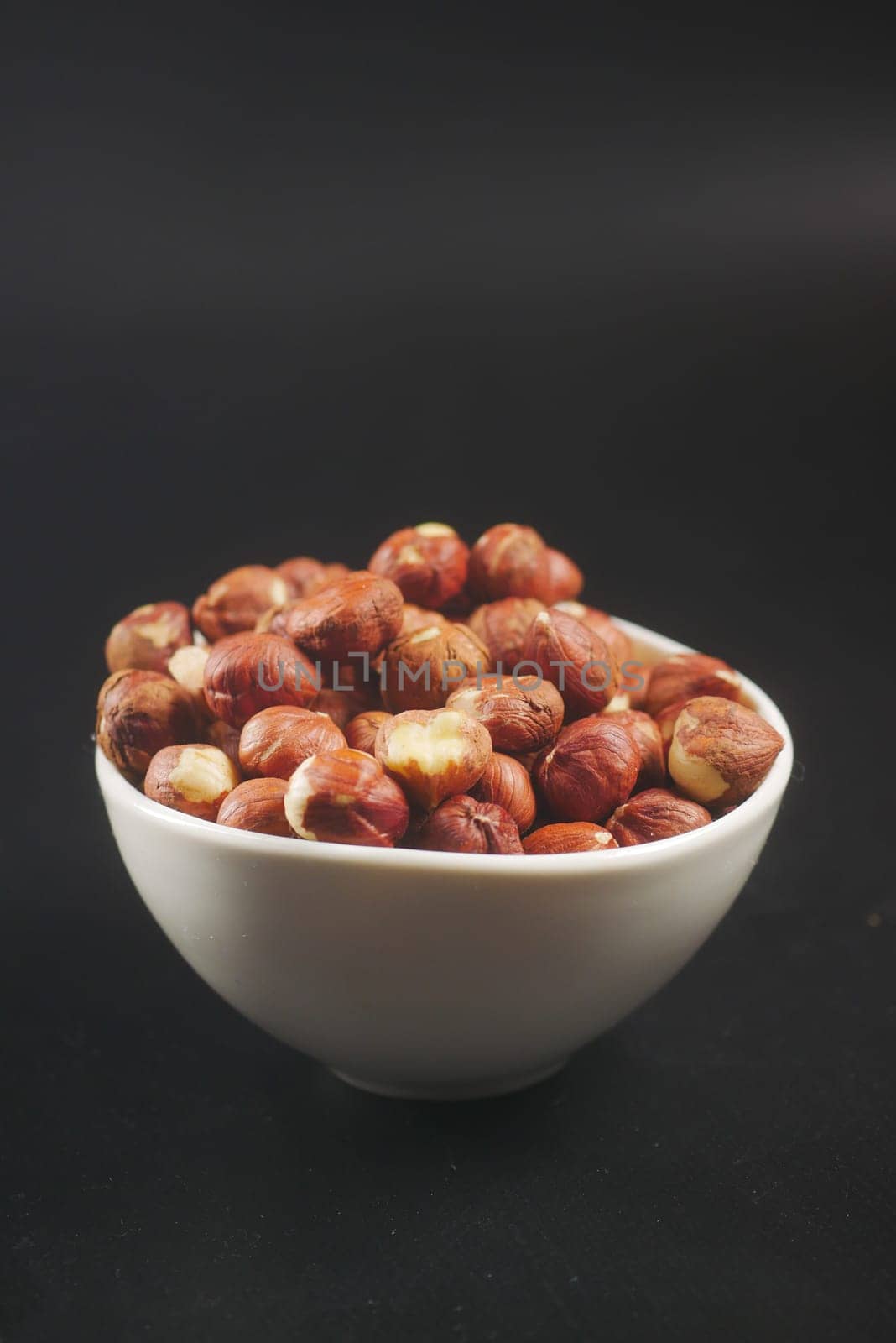 hazelnuts in a container on black background