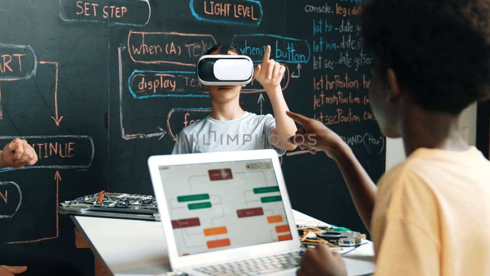 African boy programing system while caucasian girl enter metaverse while sitting at blackboard with engineering code written.Highschool girl wearing VR or headset in STEM technology. Edification.