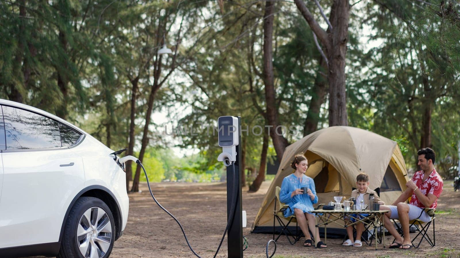 Outdoor adventure and family vacation camping in nature travel by eco friendly car for sustainable future. Lovely family recharge EV car with EV charging station in campsite. Perpetual