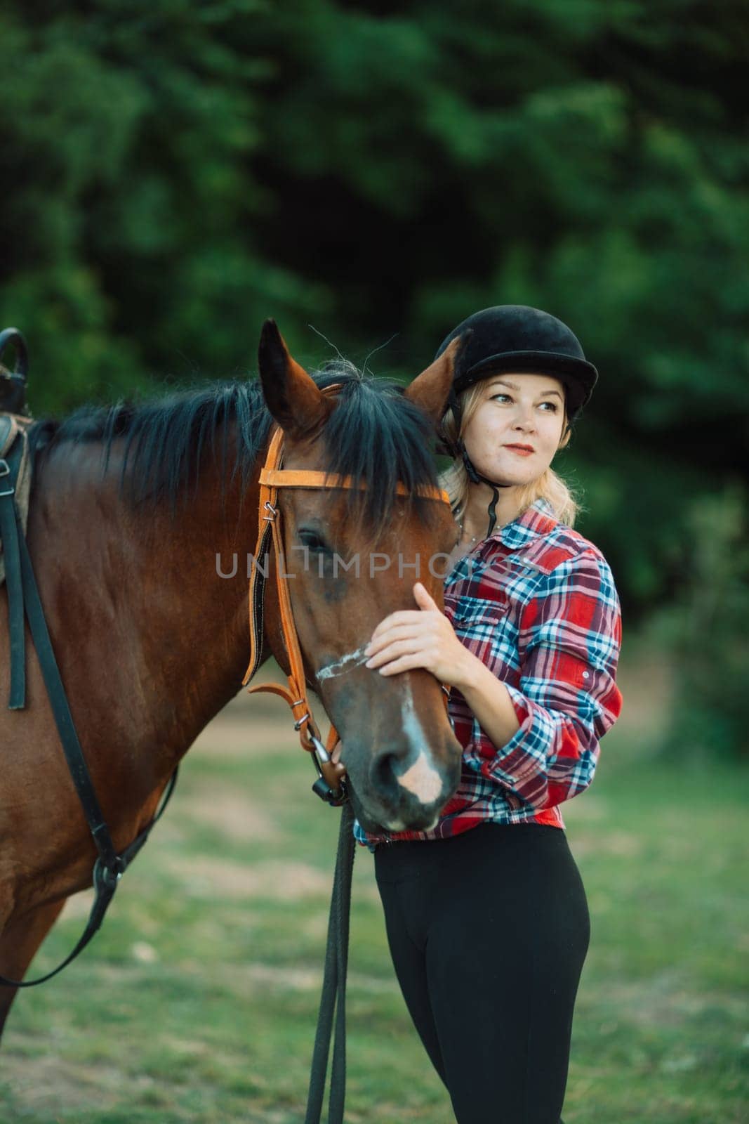 Happy blonde with horse in forest. Woman and a horse walking through the field during the day. Dressed in a plaid shirt and black leggings. by Matiunina