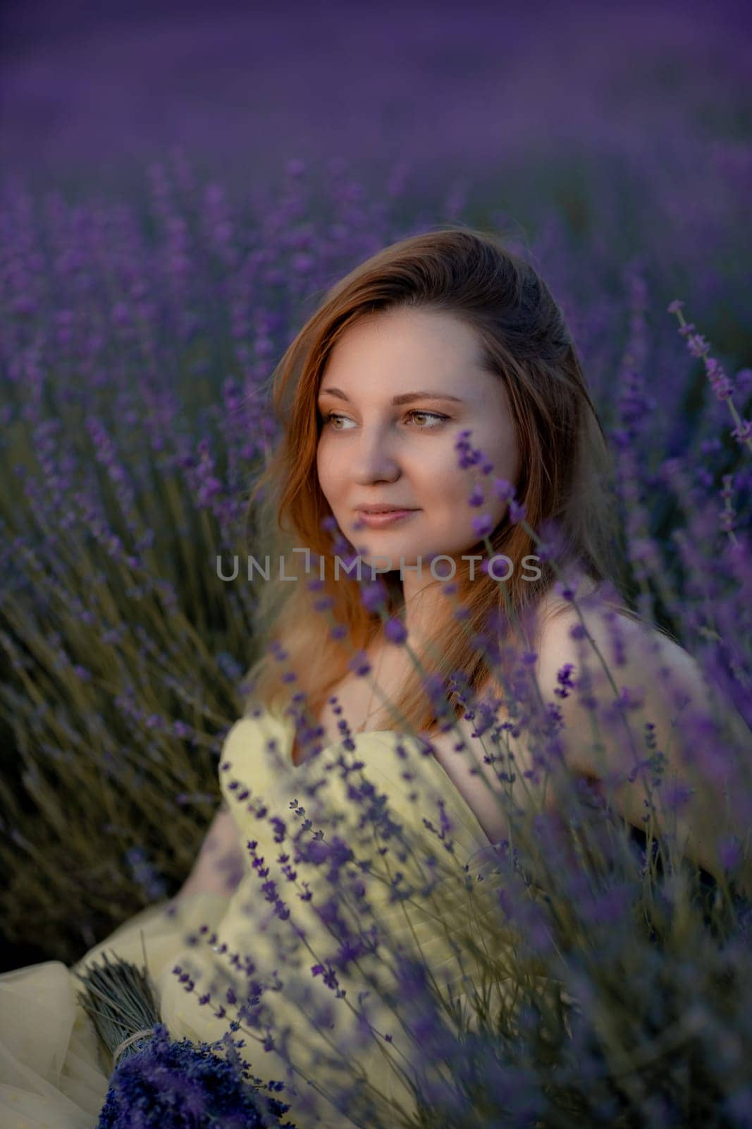 Woman poses in lavender field at sunset. Happy woman in yellow dress holds lavender bouquet. Aromatherapy concept, lavender oil, photo session in lavender by Matiunina