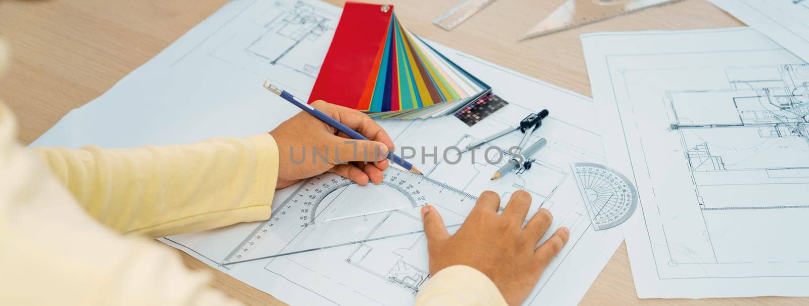 Cropped image of professional architect designer hand draws blueprint while project manager shows the mistake point with architectural document, color palette scatter around. Closeup. Variegated.