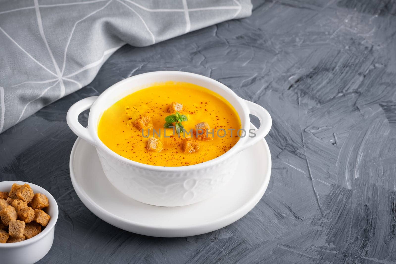 Pumpkin soup with croutons on grey background, with copy space for text.