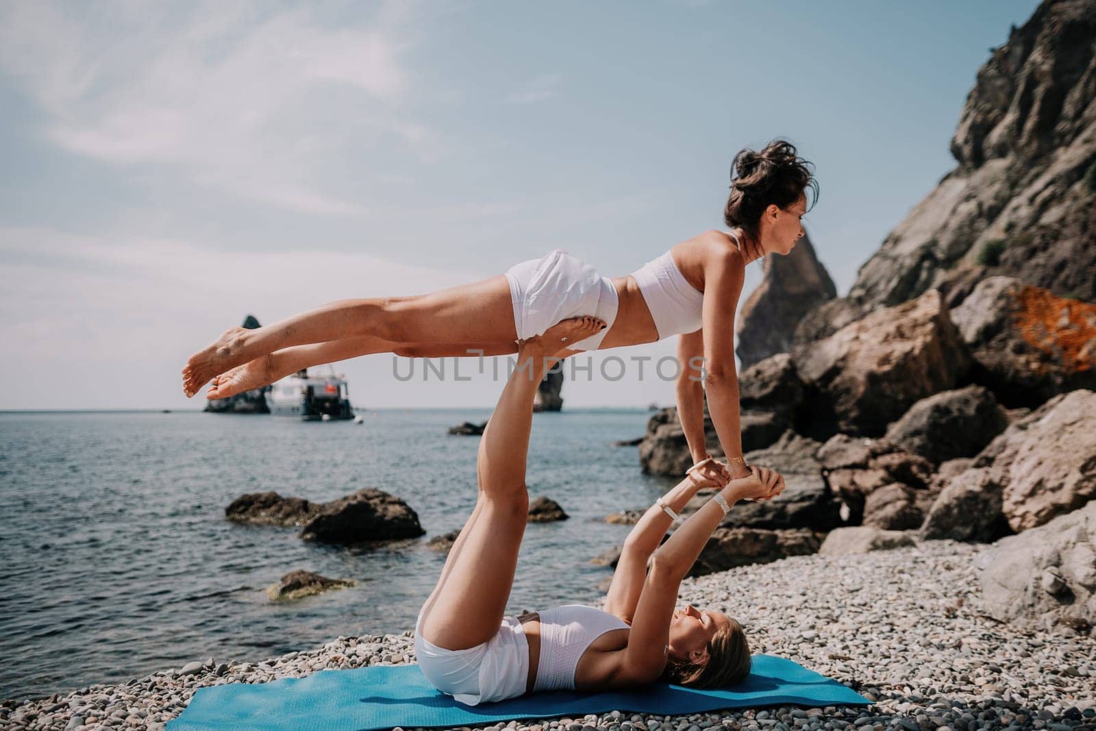 Woman sea yoga. Back view of free calm happy satisfied woman with long hair standing on top rock with yoga position against of sky by the sea. Healthy lifestyle outdoors in nature, fitness concept.