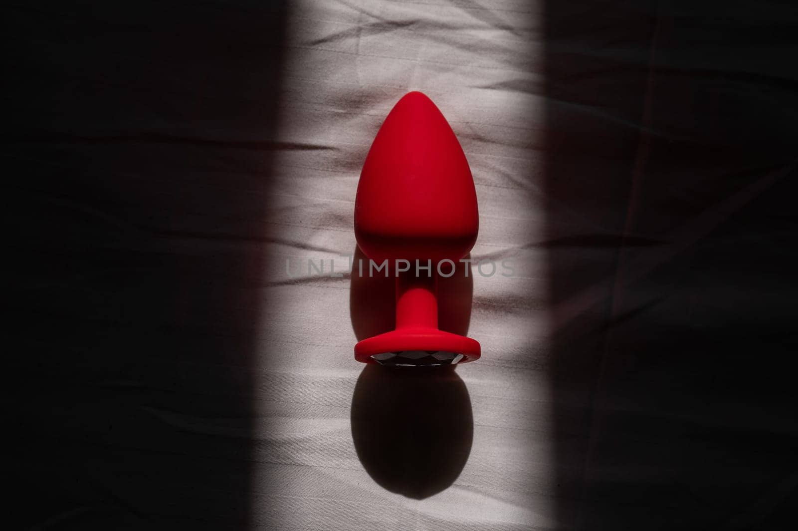Red silicone anal plug on a white sheet