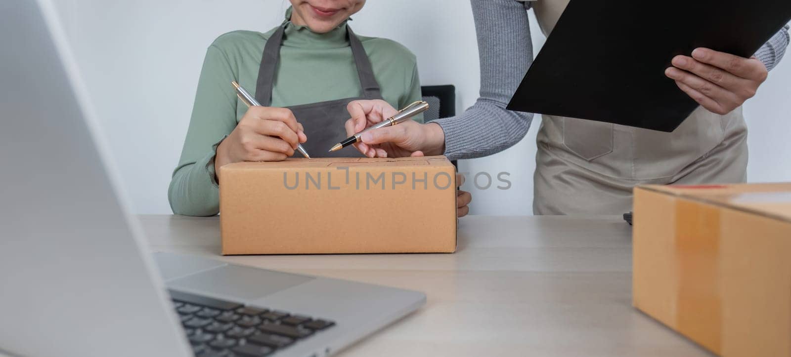 Online salespeople are selling products through online platforms and packing them into parcel boxes to prepare for delivery. by wichayada