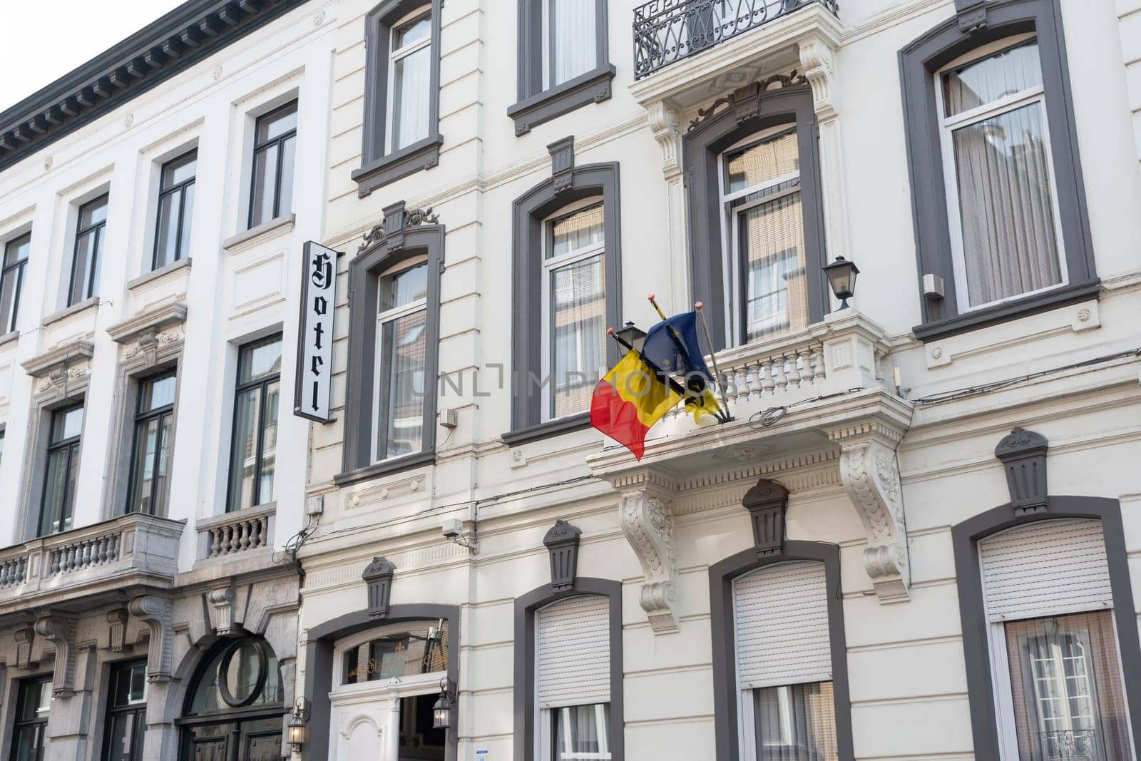 Belgian and European flags on the balcony of the historic Station Hotel building in Aalst Belgium on a sunny summer day, the concept of peace and prosperity in the country, High quality photo