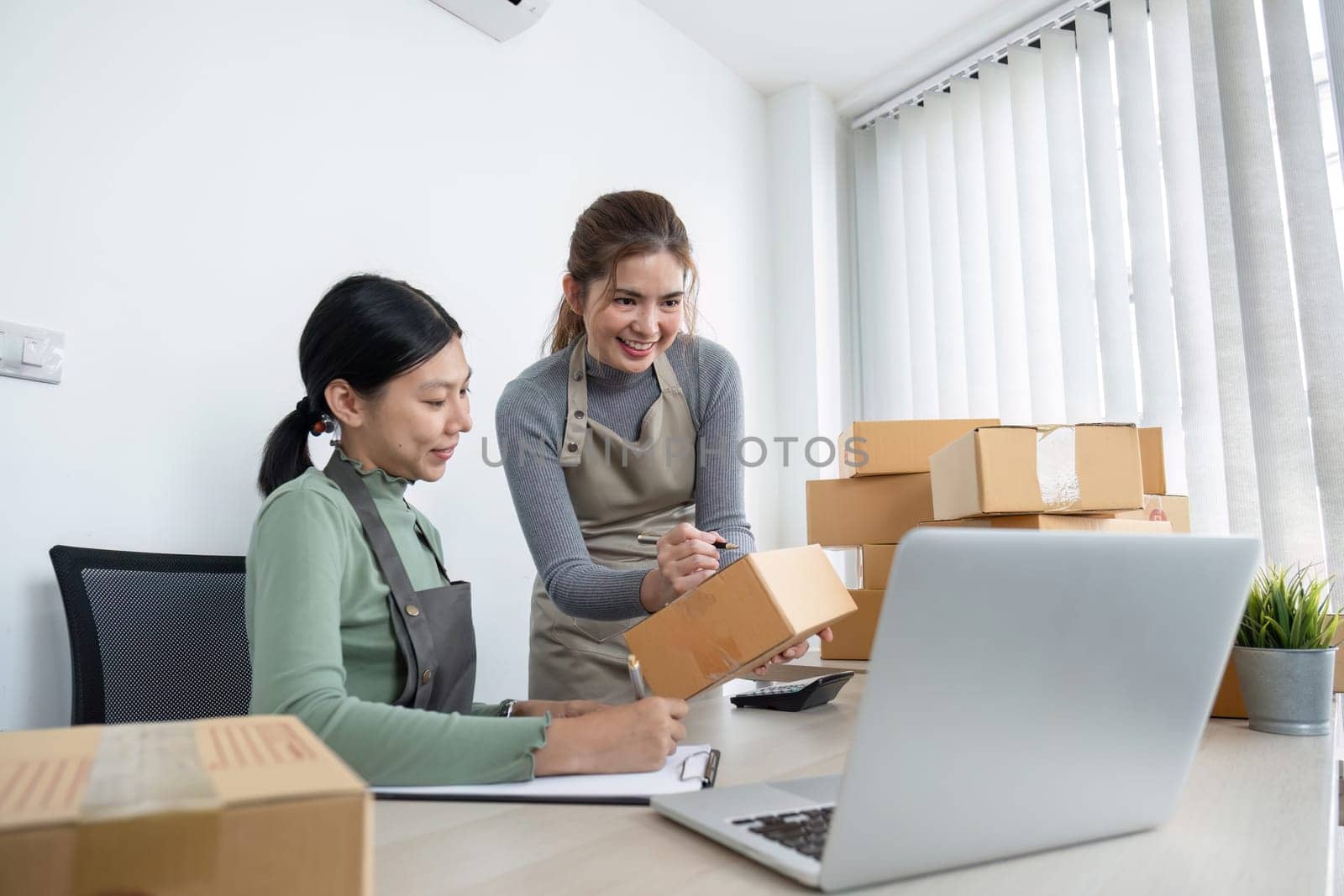 Online salespeople are selling products through online platforms and packing them into parcel boxes to prepare for delivery. by wichayada