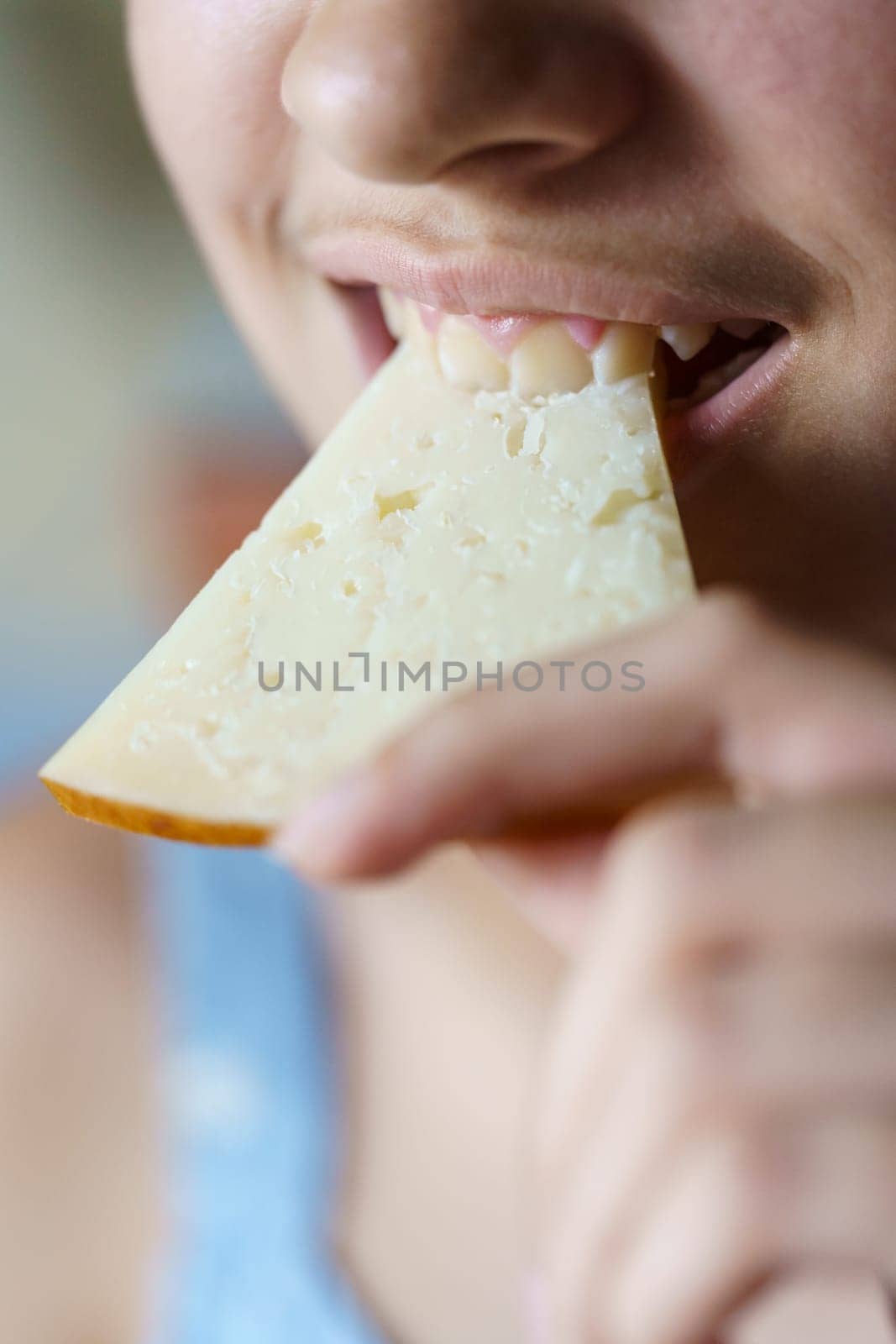 Closeup of crop happy anonymous teenage girl biting fresh cheese slice at home