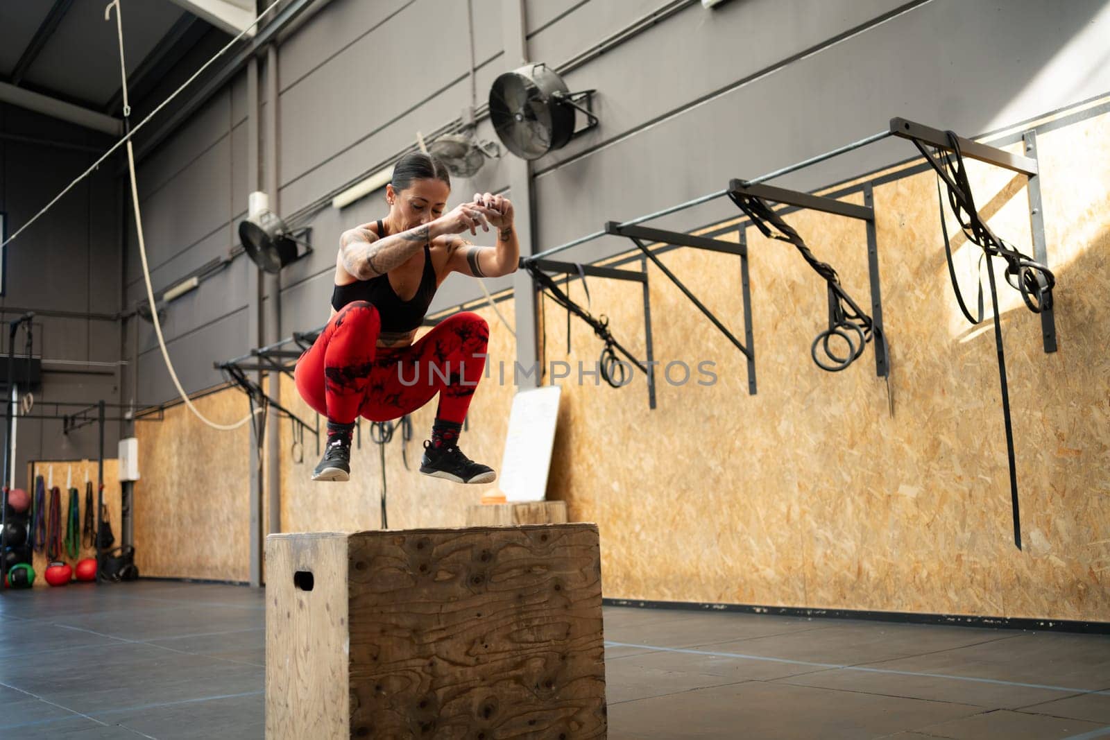 Woman jumping on a box in a cross training gym by javiindy