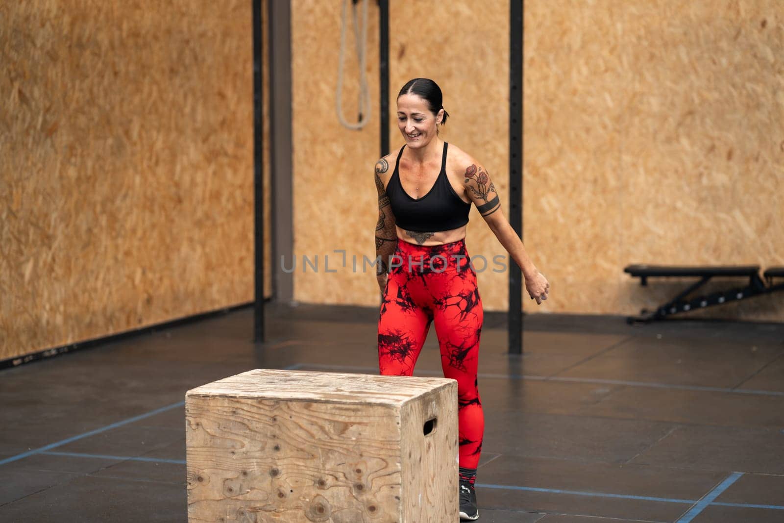 Strong woman about to jump into box in a gym by javiindy