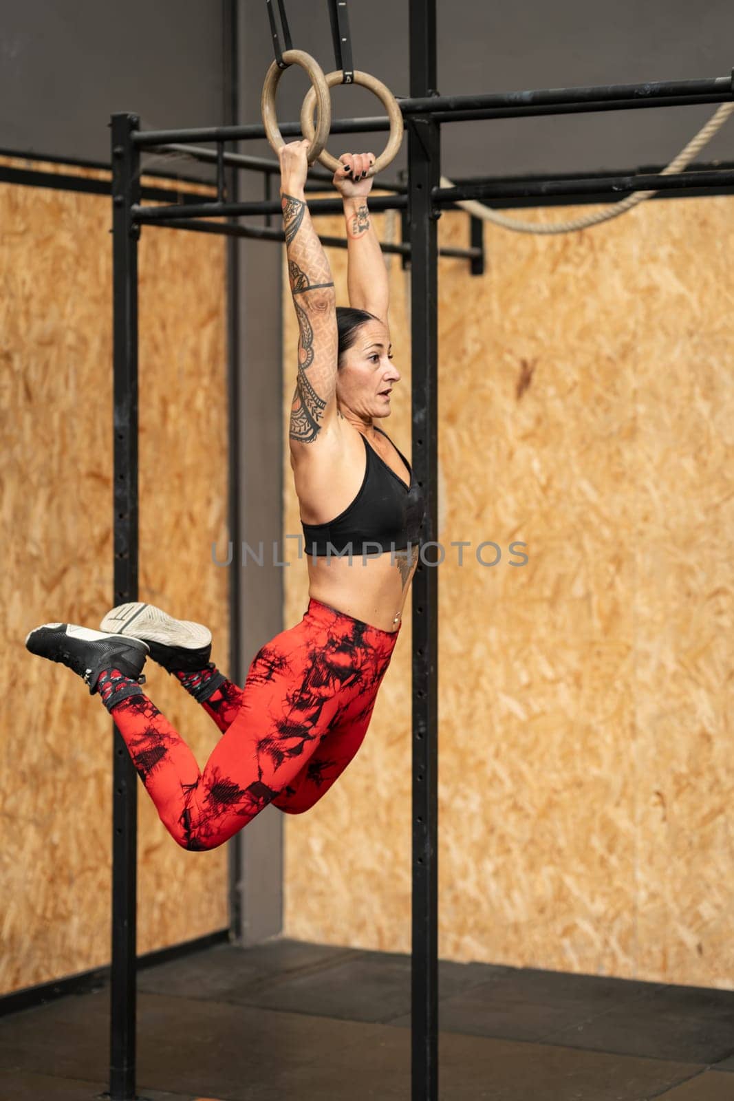 Female athlete training with olympic rings in a gym by javiindy