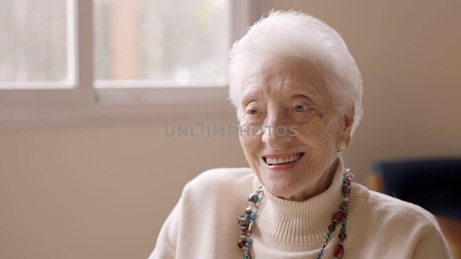 Old woman with white hair smiling at camera in a geriatric looking to the copy space