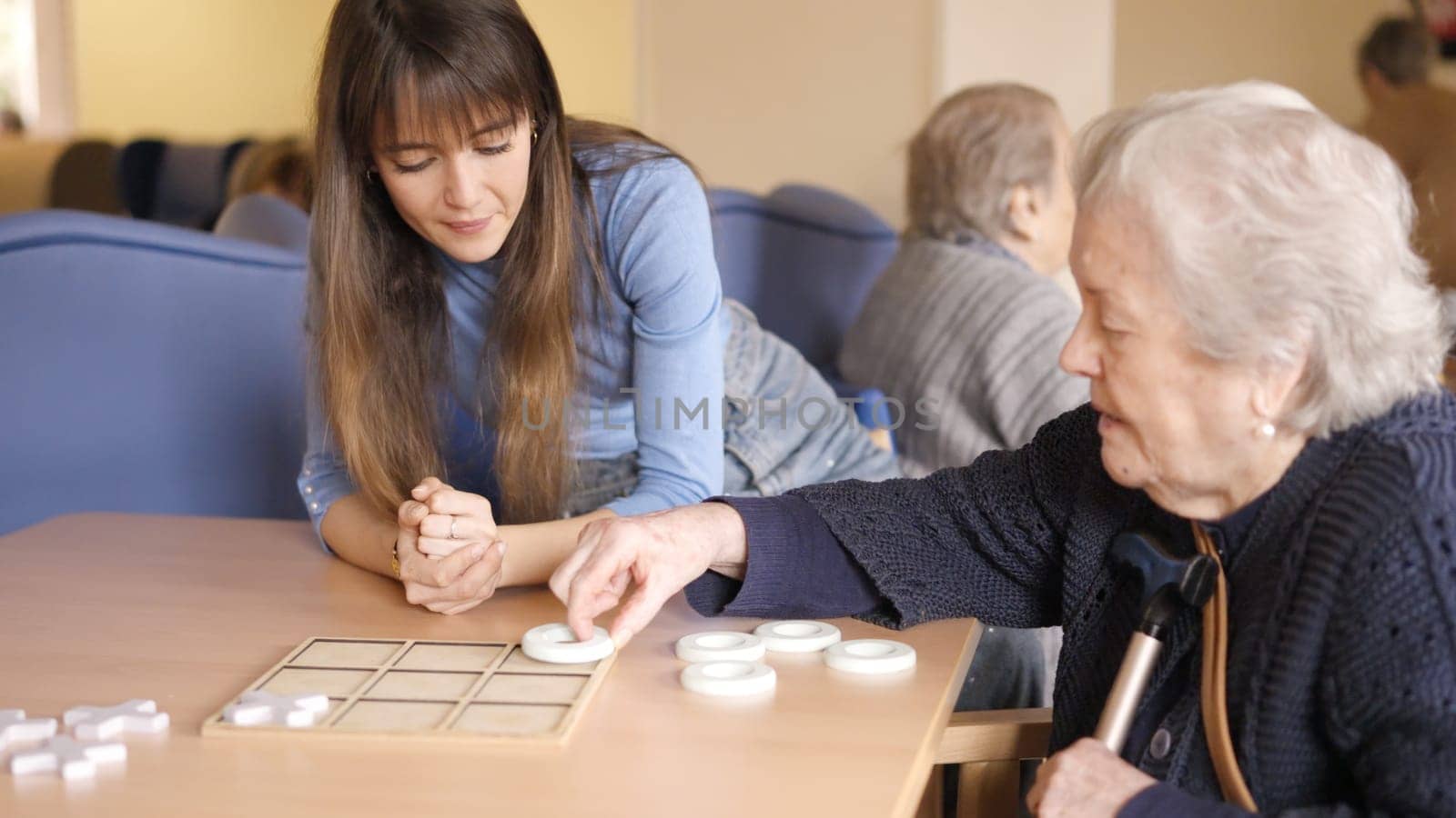 Senior woman playing board game with a woman contemplating it