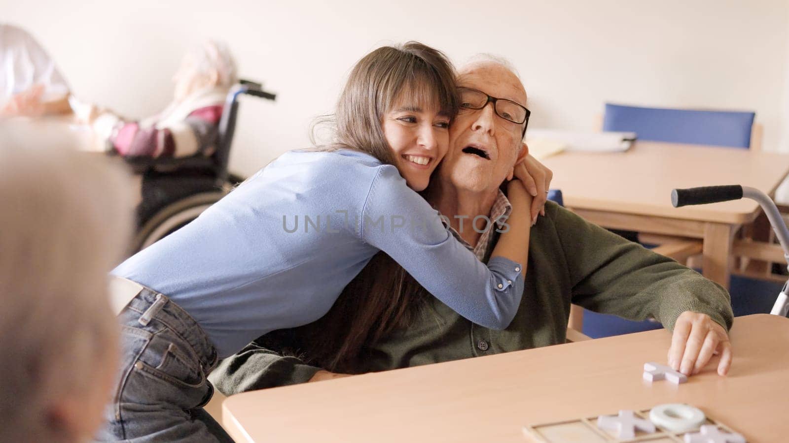 Happy granddaughter embracing her senior grandfather in a geriatric