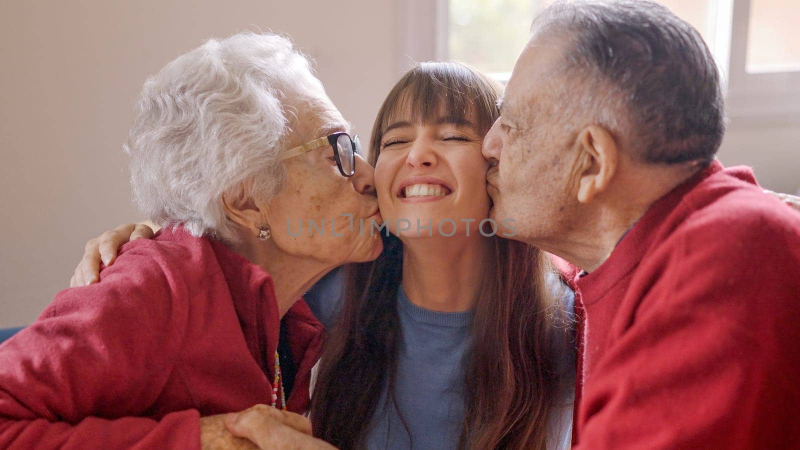 Happy grandparents kissing their granddaughter while she visits them