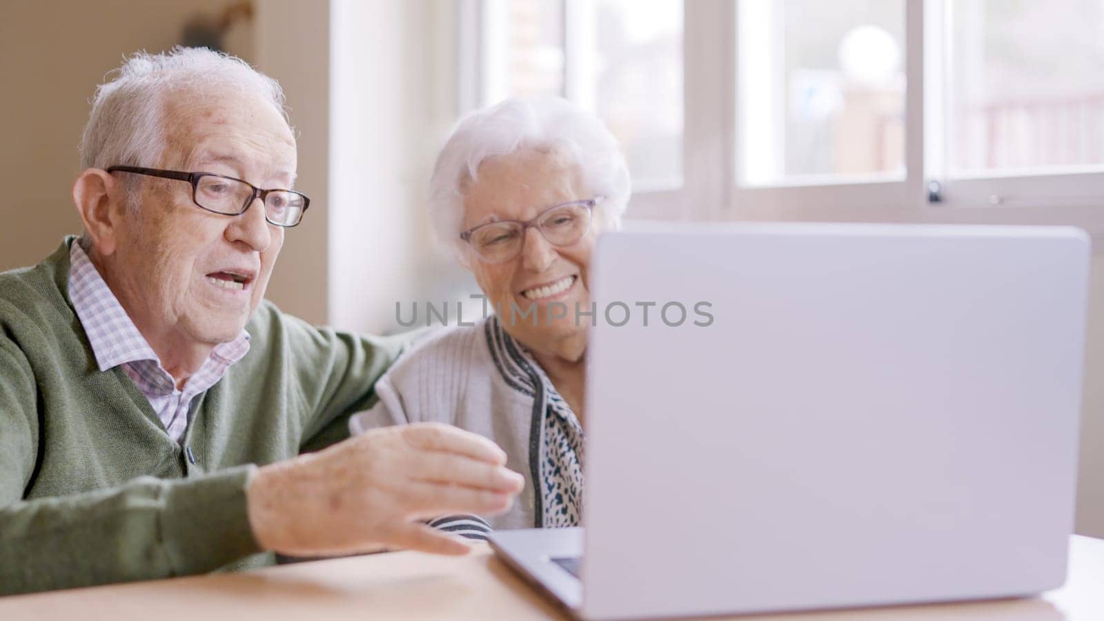 Senior people talking during online meeting using laptop in geriatric by ivanmoreno