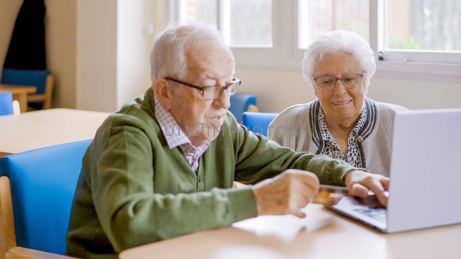 Grandparents shopping online using credit card and laptop at home