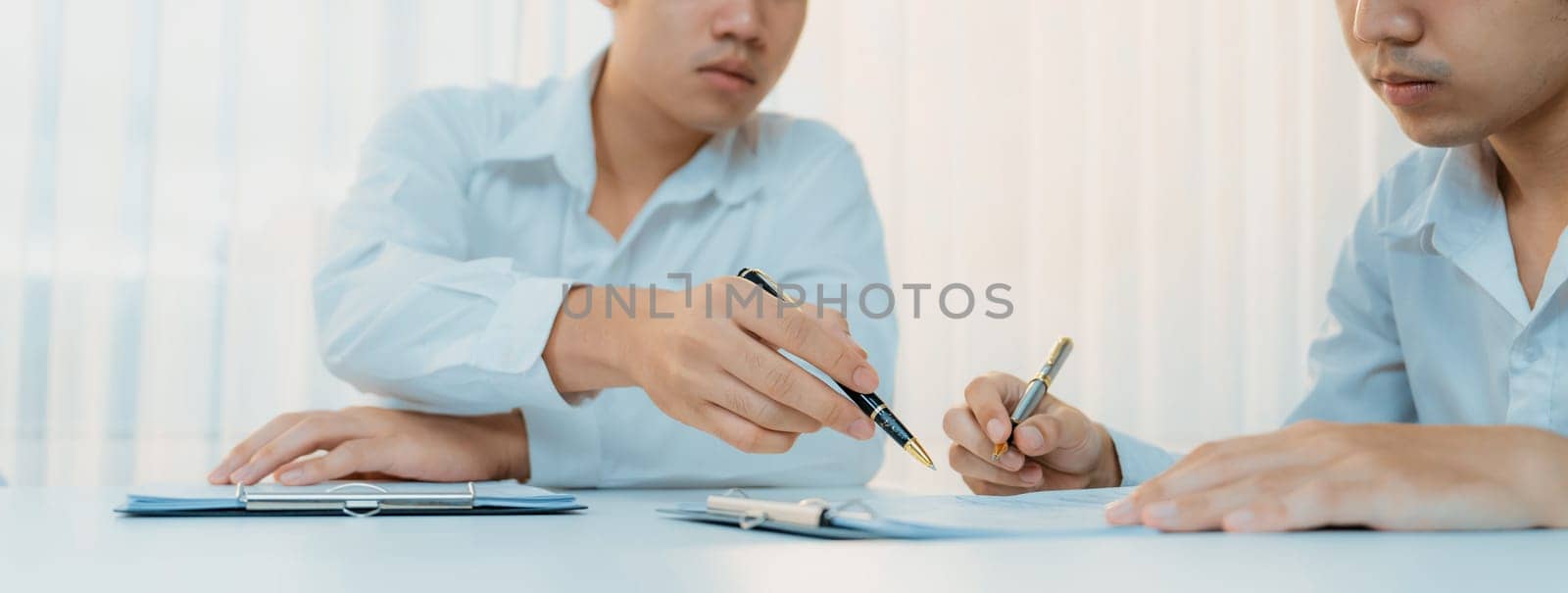 Business executive signing contract agreement document on the bale with the help from company attorney or lawyer service in law firm office. Business investing and finalizing legal processing. Shrewd