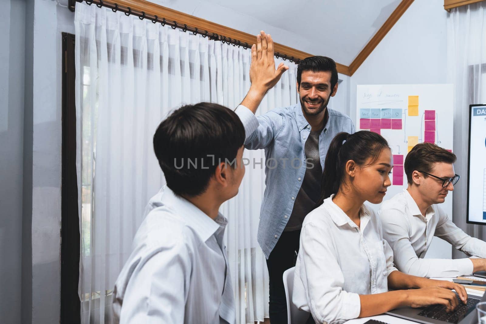 Analyst team leader celebrate and high five together with his colleague after successful data analysis meeting using FIntech software power with business intelligence or BI dashboard. Prudent