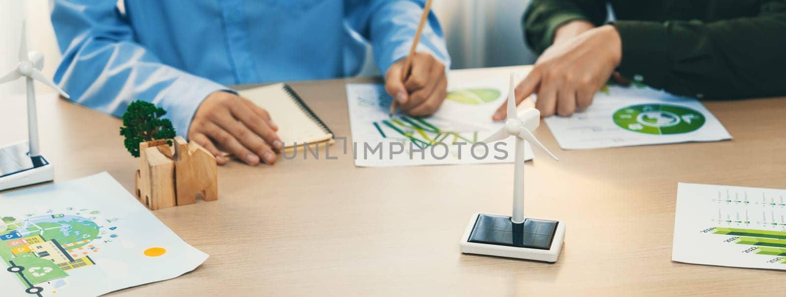 Business people invest in green business plan at meeting room on table with house model and wind mill placed represented eco house and renewable energy. Closeup. Delineation.