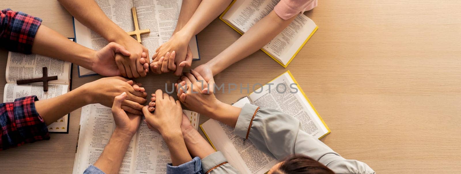 Group of people praying together while holding hand. Top view. Burgeoning. by biancoblue