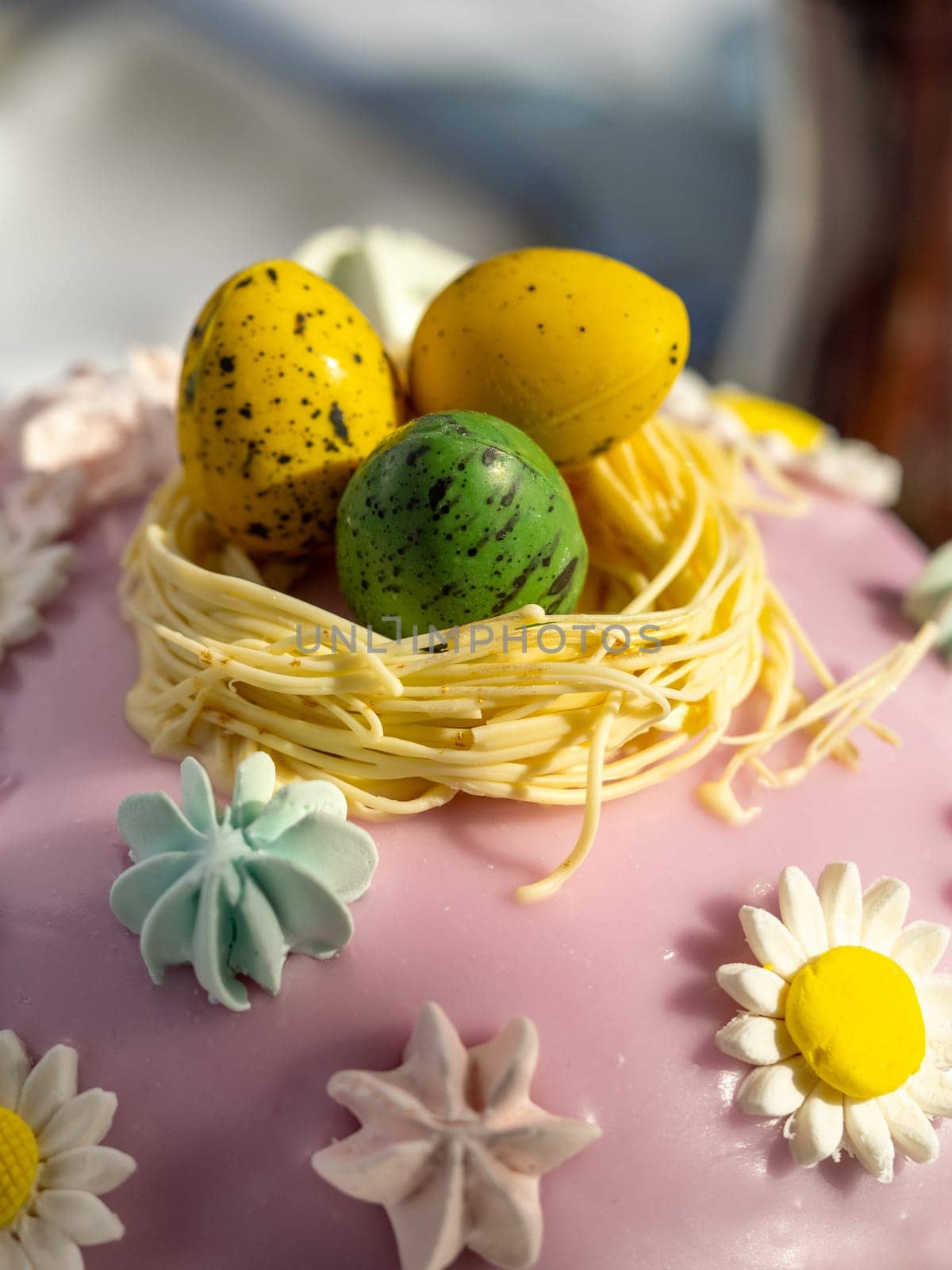 Delicious Easter cake with sugar glaze decorated chocolate eggs and merengue, close up. Festive orthodox easter cake kulich on the table and willow on background