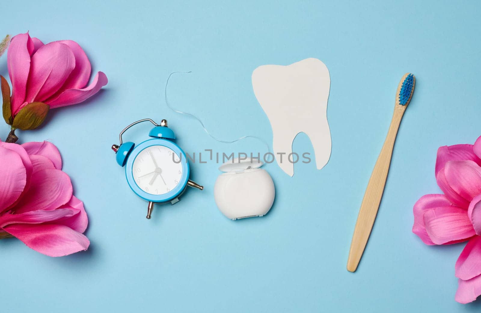 Dental floss and paper teeth on blue background, oral hygiene by ndanko