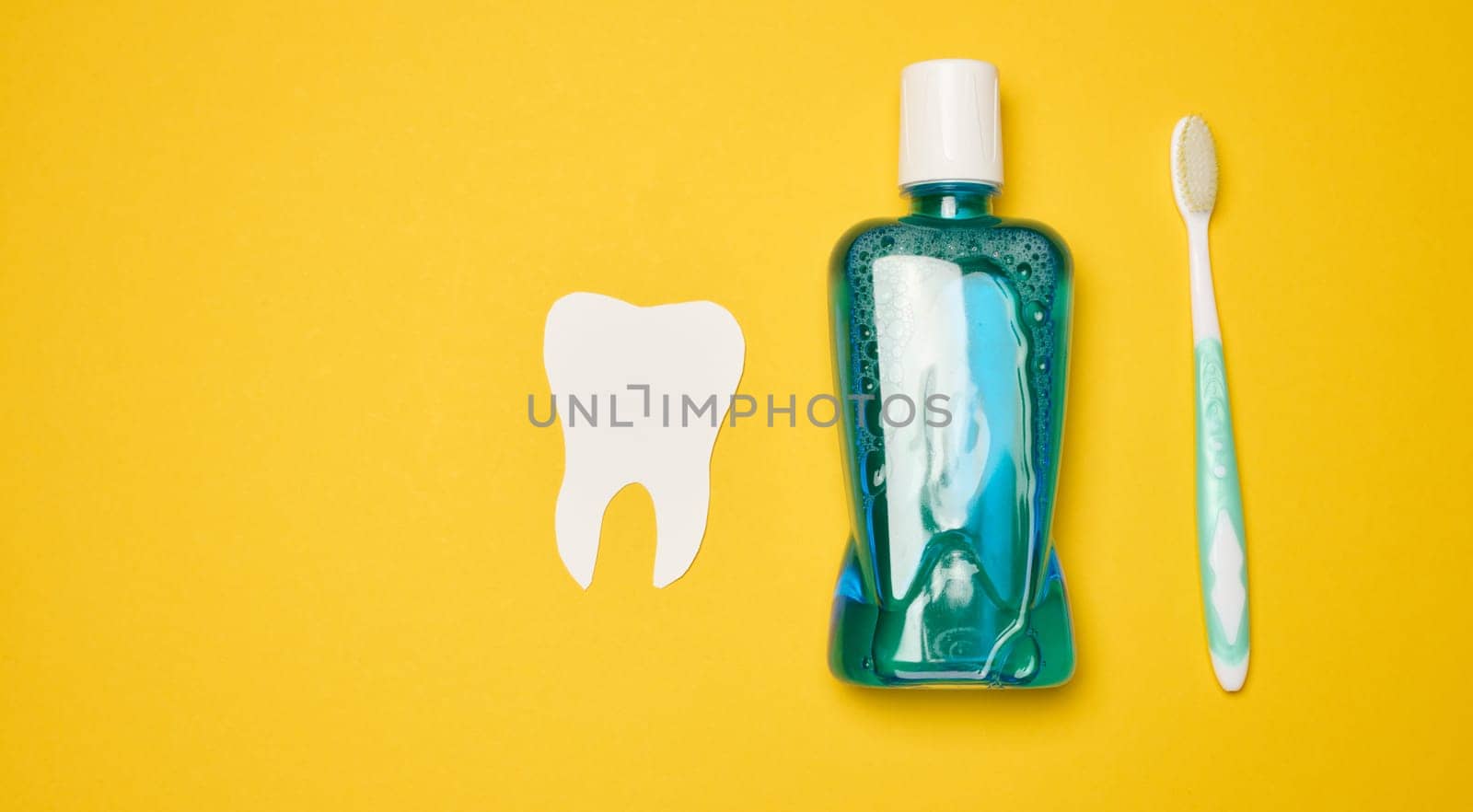 Mouthwash and toothbrush on yellow background, top view