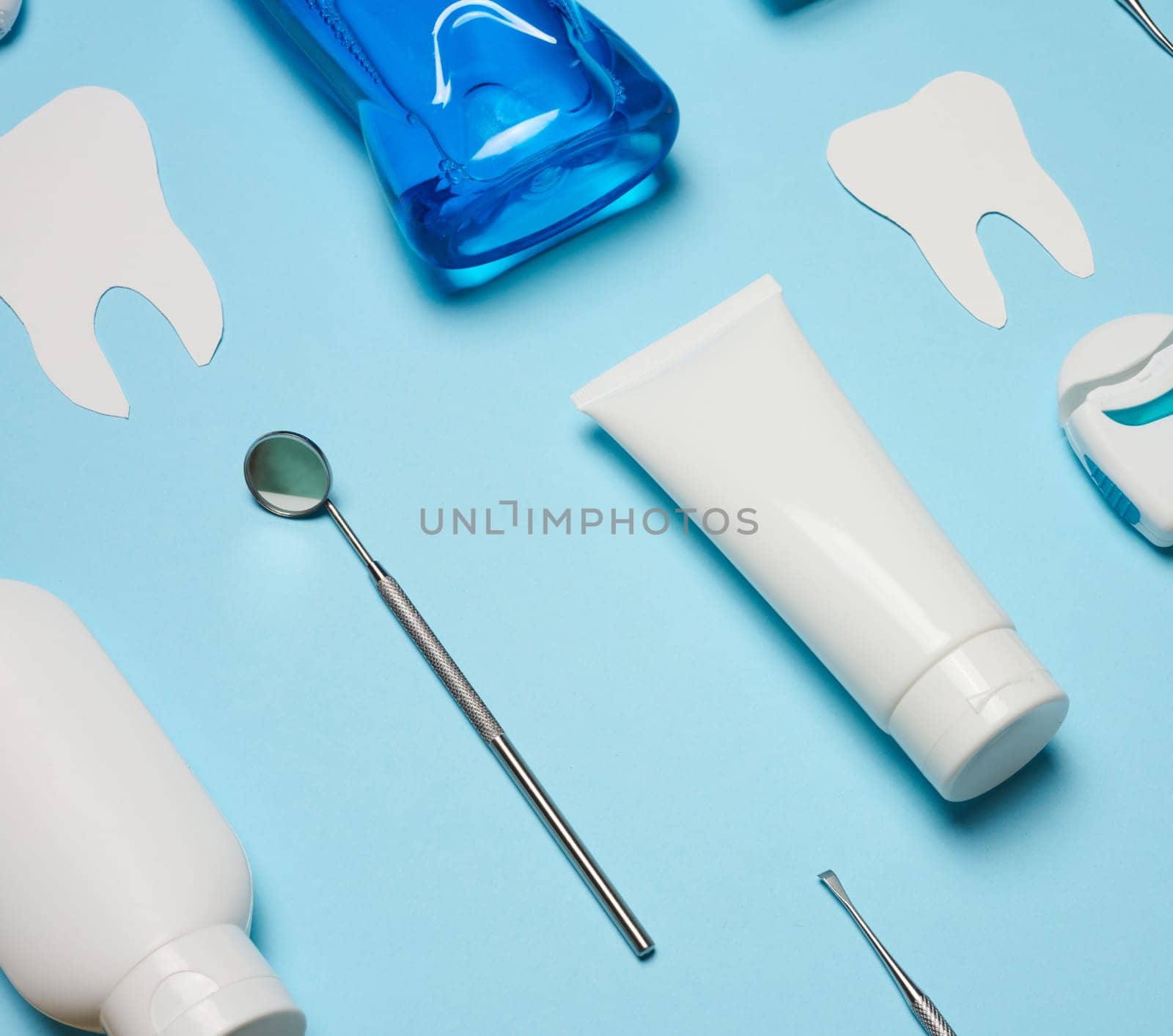 Mouthwash, toothpaste tube, dental floss and medical mirror on a blue background, oral hygiene. Top view by ndanko