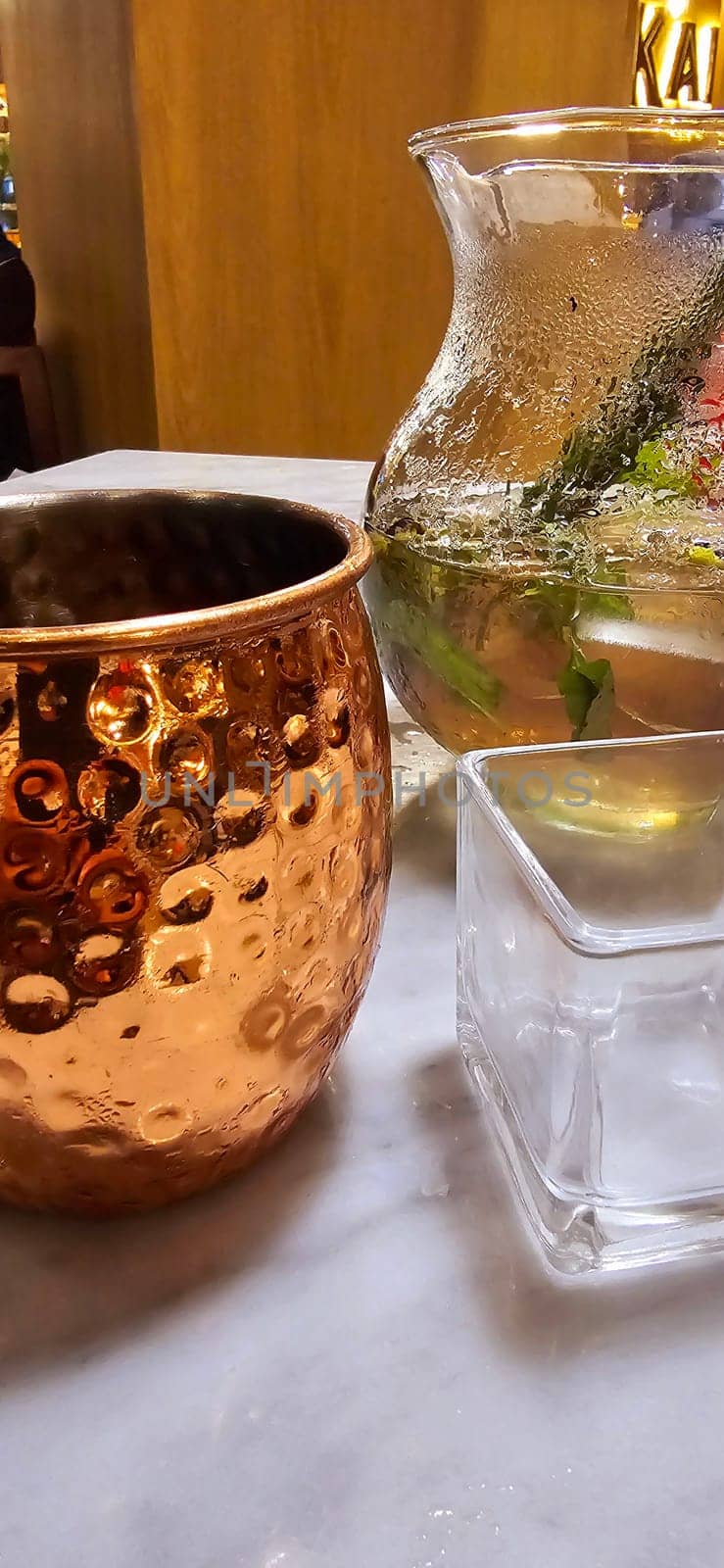 Traditional iced tea served in a unique and artistic brass cup , ice tea garnished with rosemary twigs in a restaurant