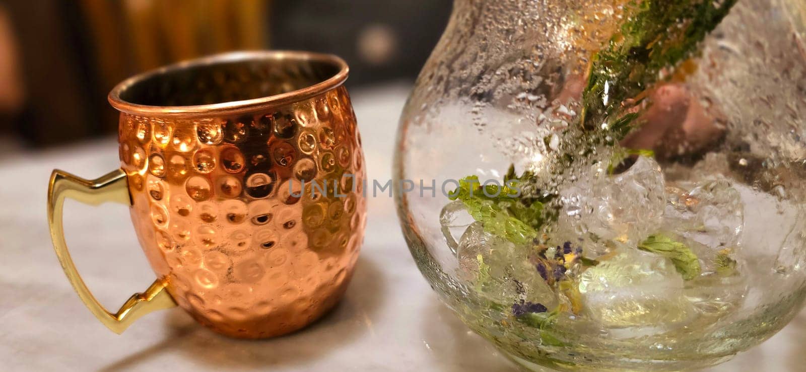 Traditional iced tea served in a unique and artistic brass cup , ice tea garnished with rosemary twigs in a restaurant