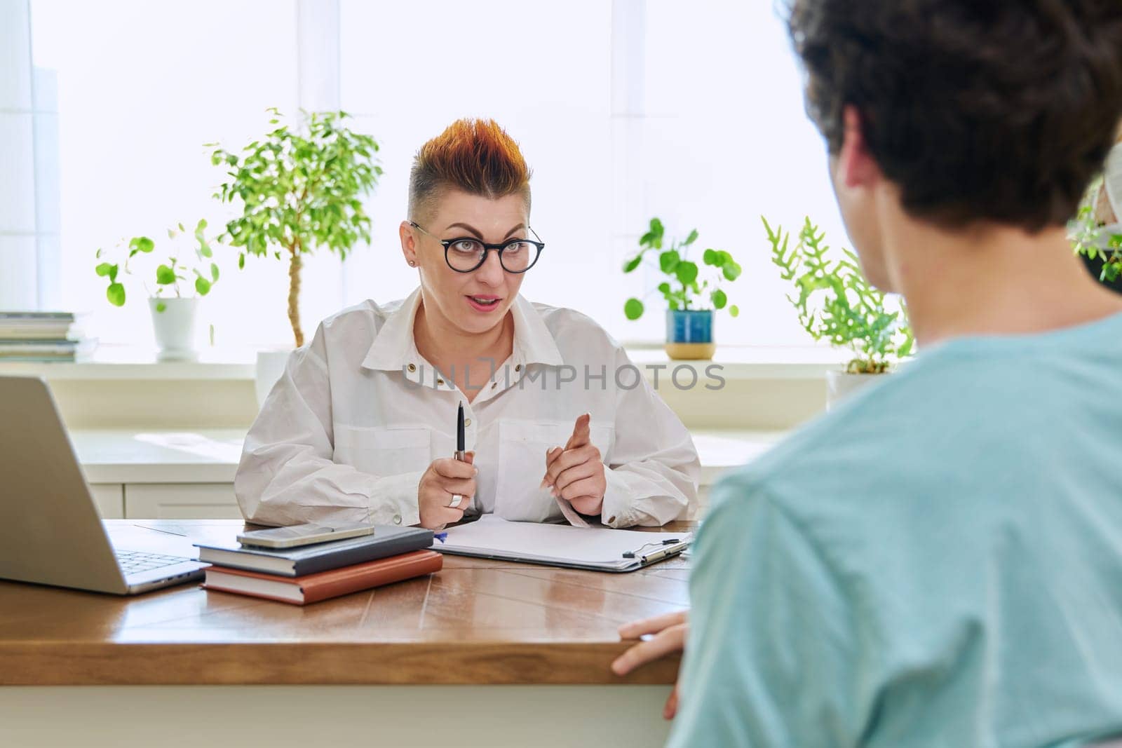 Middle-aged female professional psychologist mental therapist talking with young man in office. Psychotherapist advisor working with male patient. Psychology psychotherapy support treatment assistance