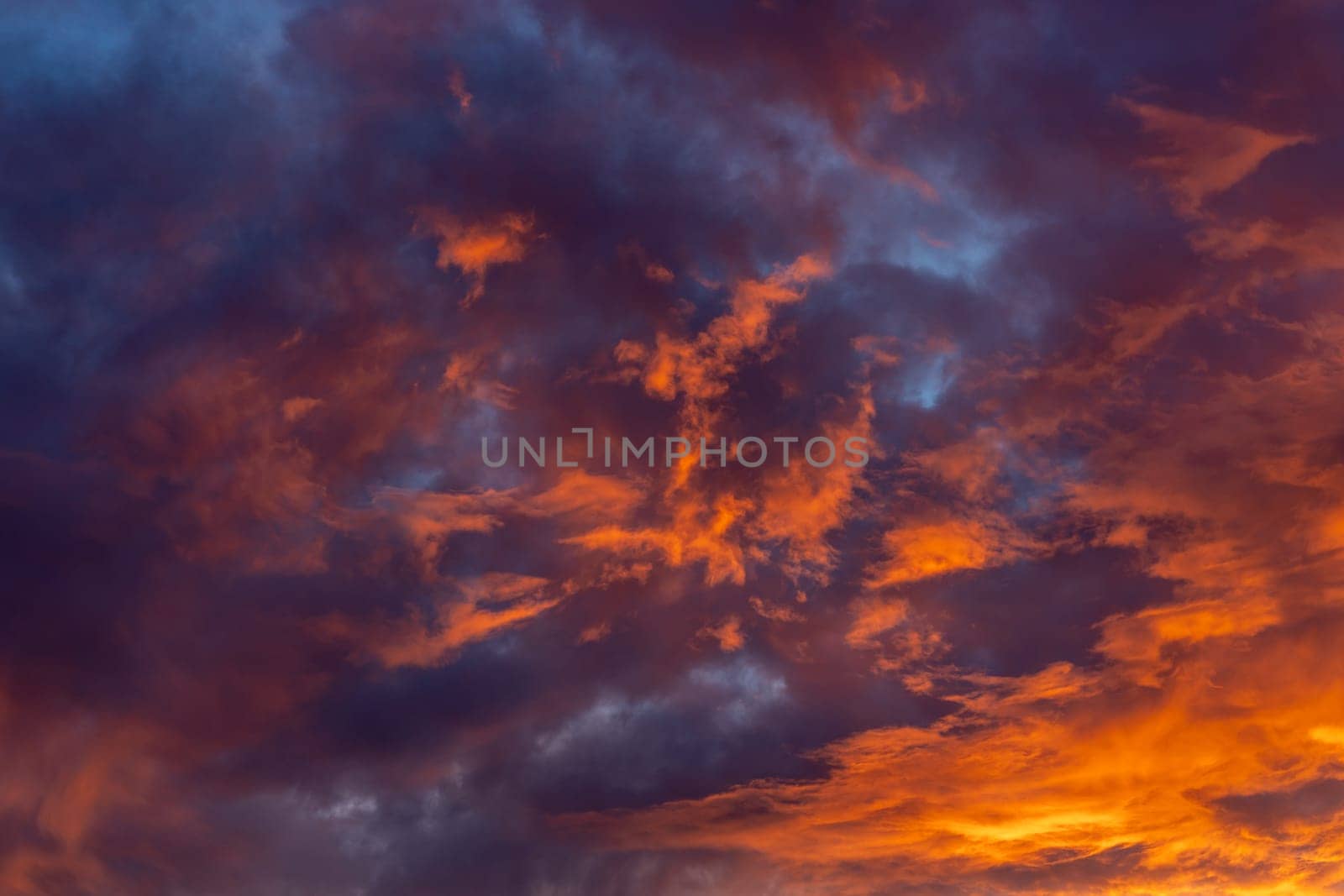Dramatic fiery bloody sky with orange, red and purple fluffy clouds at sunset