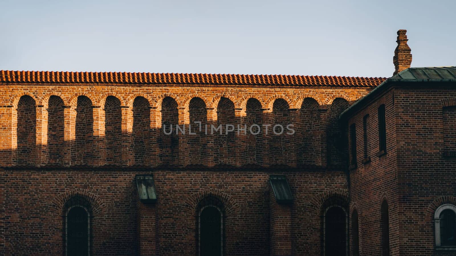 Brick facade with decorative arches, old building in Krakow at sunset, Poland