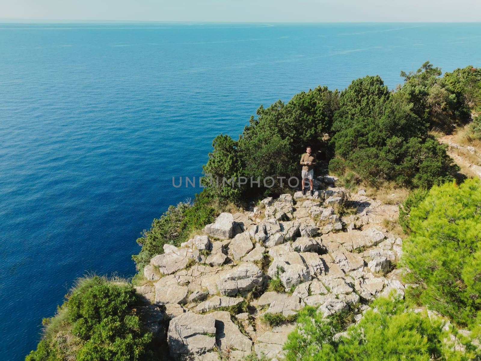 Man standing on top of mountain to control drone in Dugi Otok island, Telascica National Park, Croatia