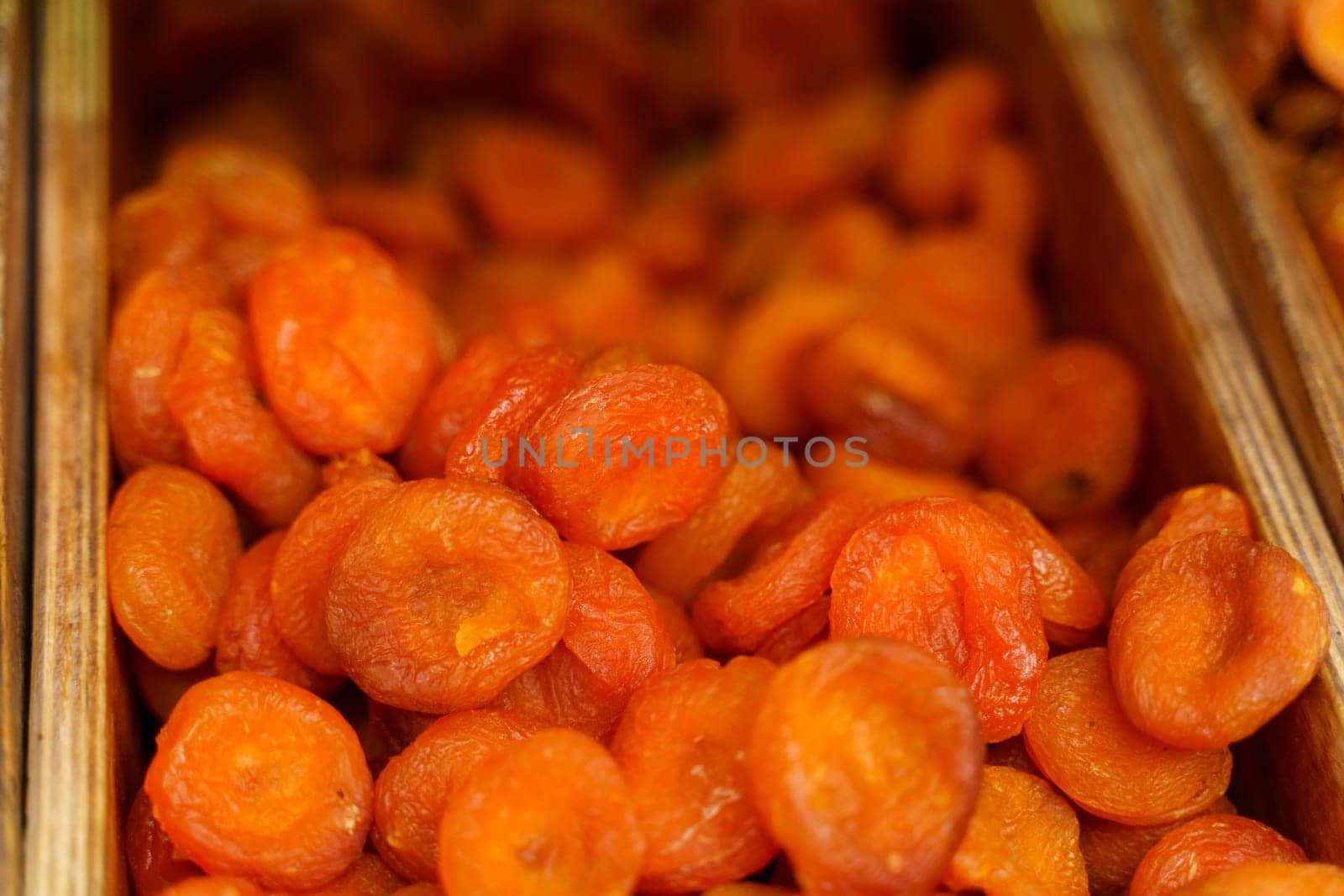 A selection of golden dried apricots showcased for sale, capturing their wrinkled texture and vibrant orange hue.