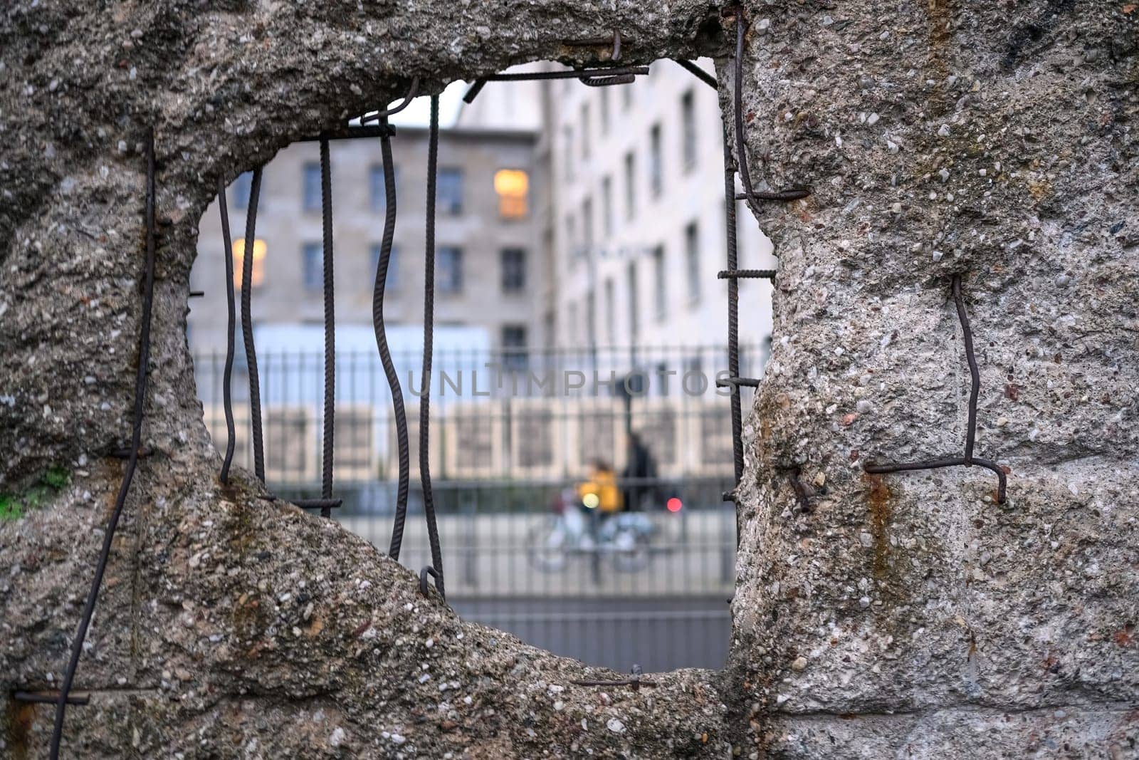 Hole in Broken Berlin wall and walking person against by GekaSkr