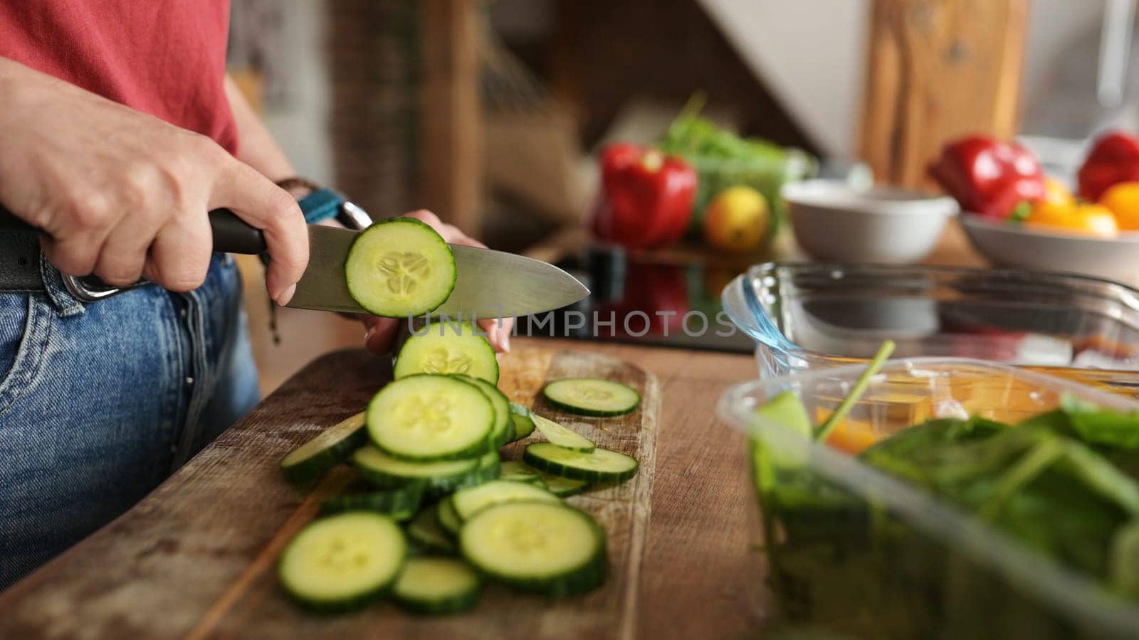 Woman Cutting Cucumbers On A Cutting Board by GekaSkr