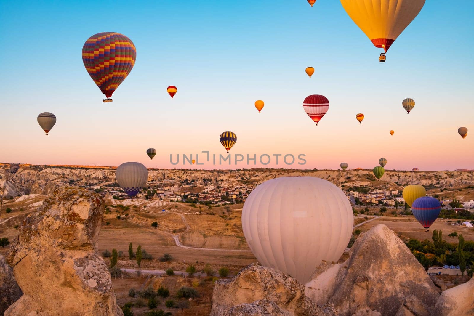 Colorful hot air balloons taking part in festival in sunset sky