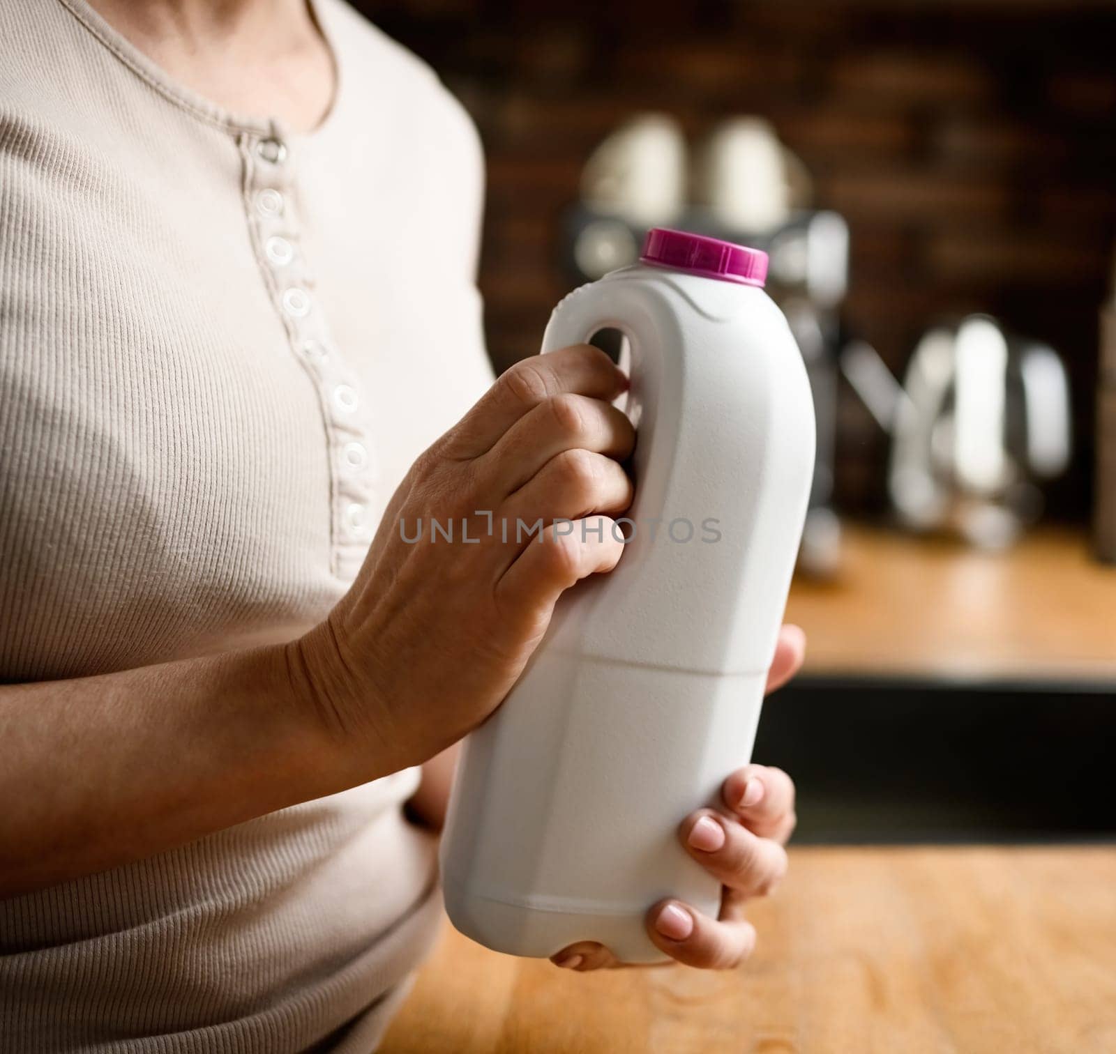 Girl holding a bottle with a bottle of milk. Woman with protein coctail drink at home