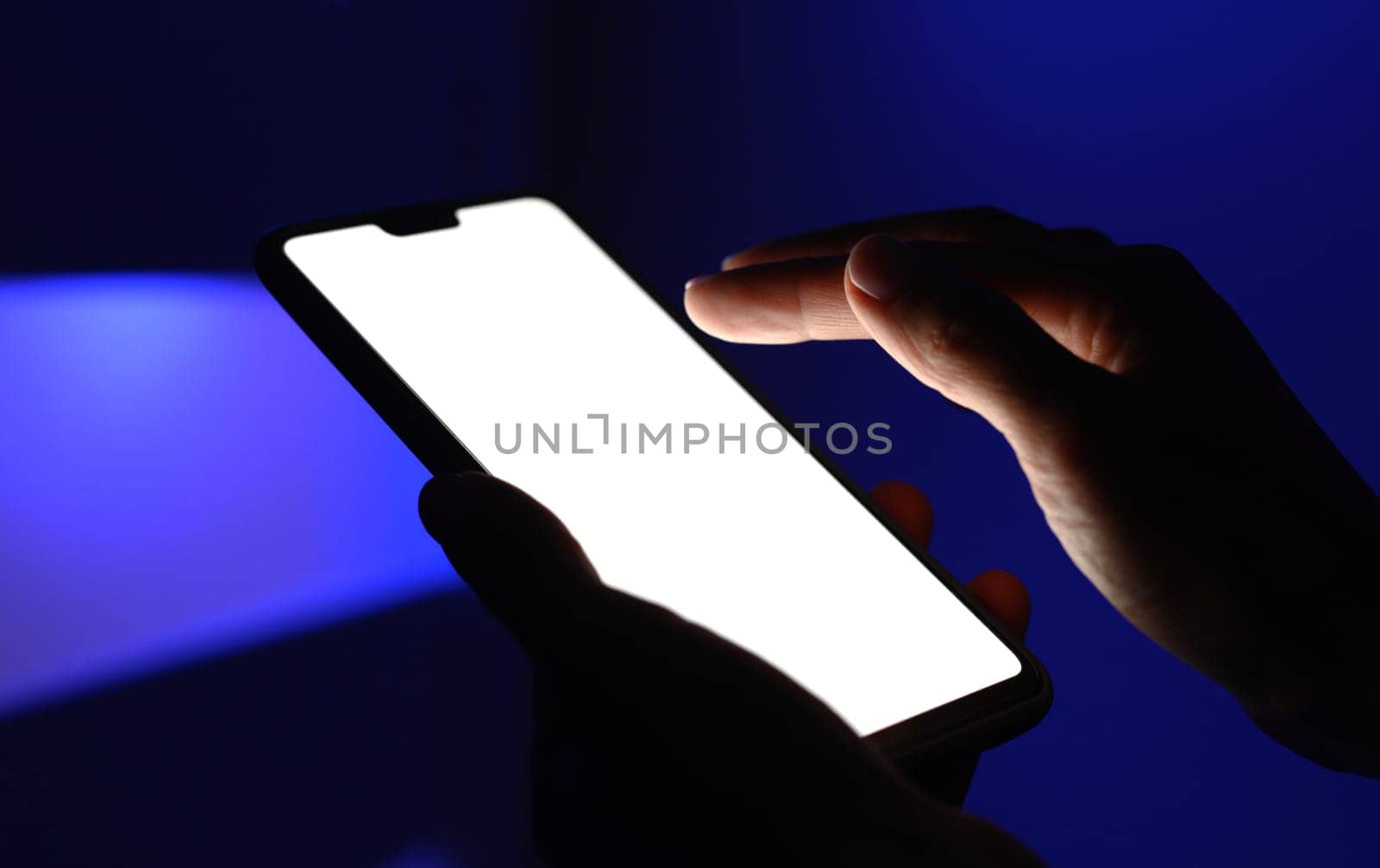 Hands holding a smart with white screen against blue blurry background