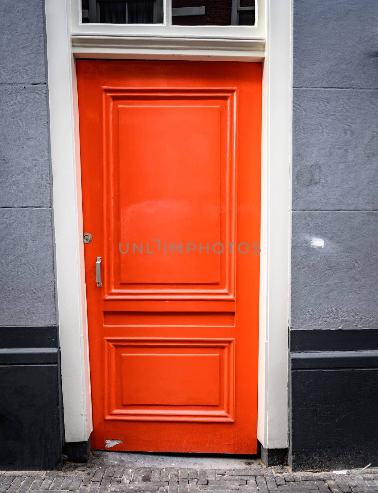 Traditional red door with design in black residential building. House entrance in european city