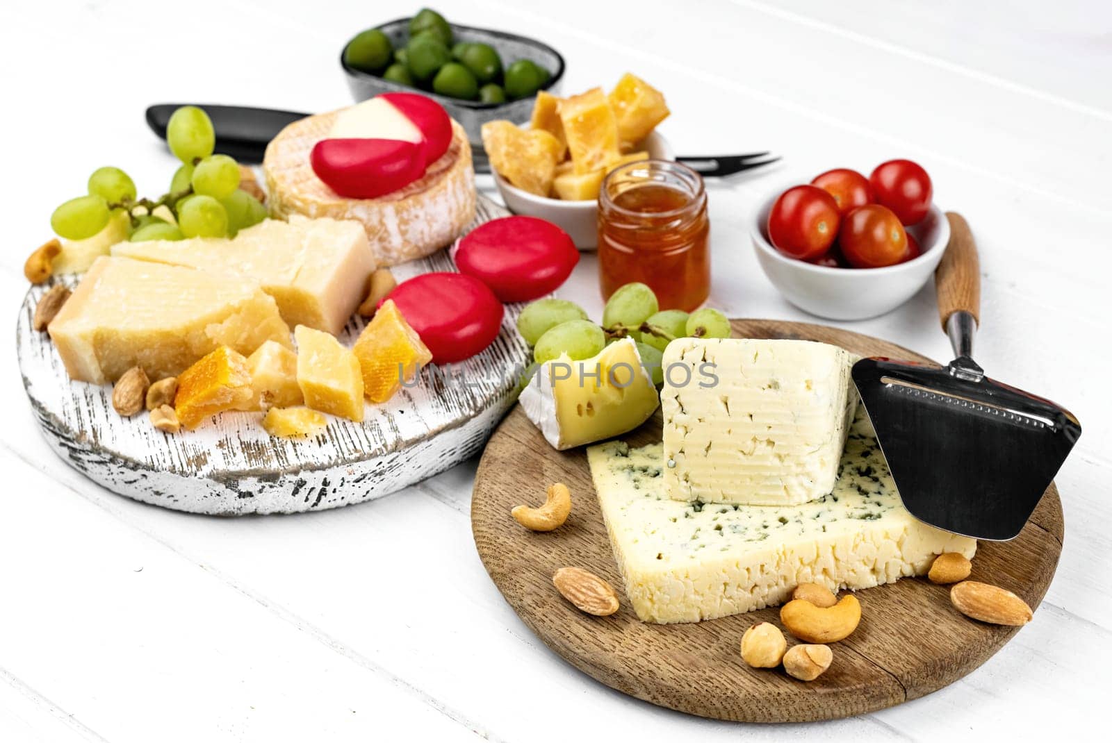 Different kinds of cheese served with green olives, tomato and grape for gourmet nutrition. Organic parmesan and brie with honey delicatessen